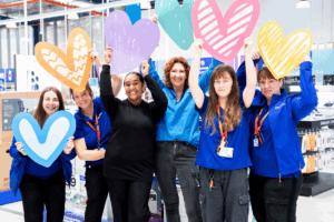A group of women joyfully holding heart-shaped paper cutouts, celebrating love and togetherness.