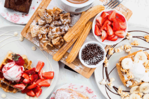 A table filled with waffles, fresh strawberries, and an assortment of colorful desserts.