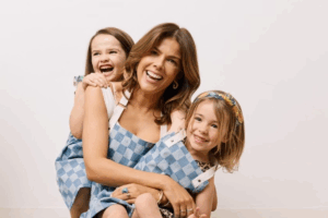 A woman and two young girls smile together for a photo, showcasing their joyful expressions.