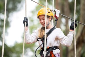 A girl in a helmet grips a rope, ready for an outdoor adventure or climbing activity.