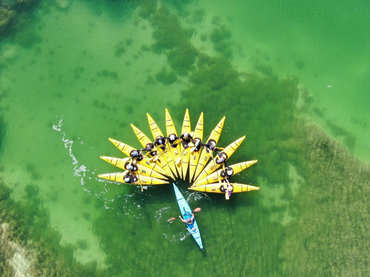 A group of people paddling together in a kayak on a calm body of water.
