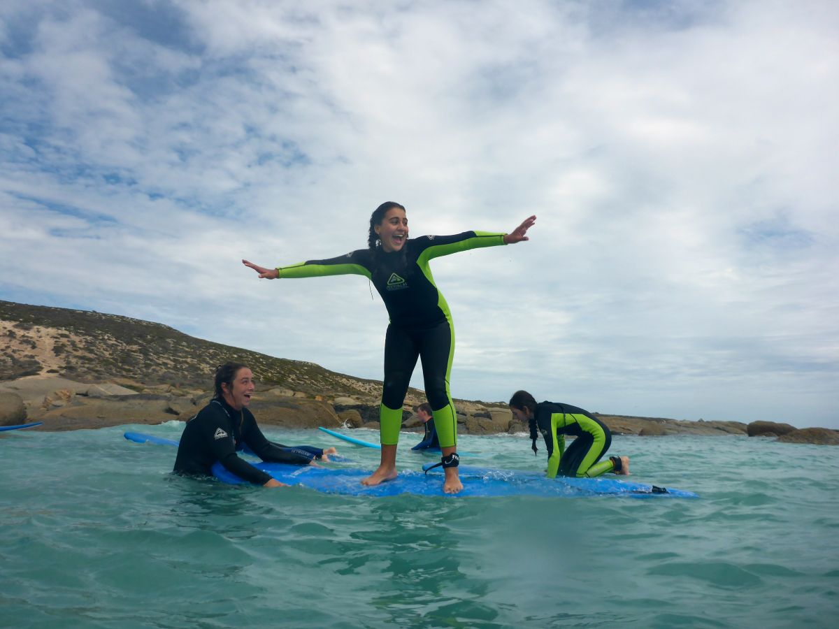 A woman in a wetsuit balances on a surfboard, riding a wave in the ocean.