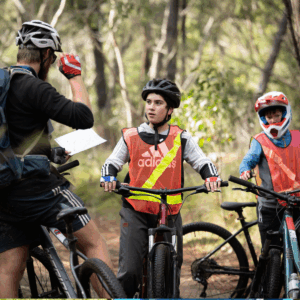 A group of cyclists riding bikes through a lush green forest trail.