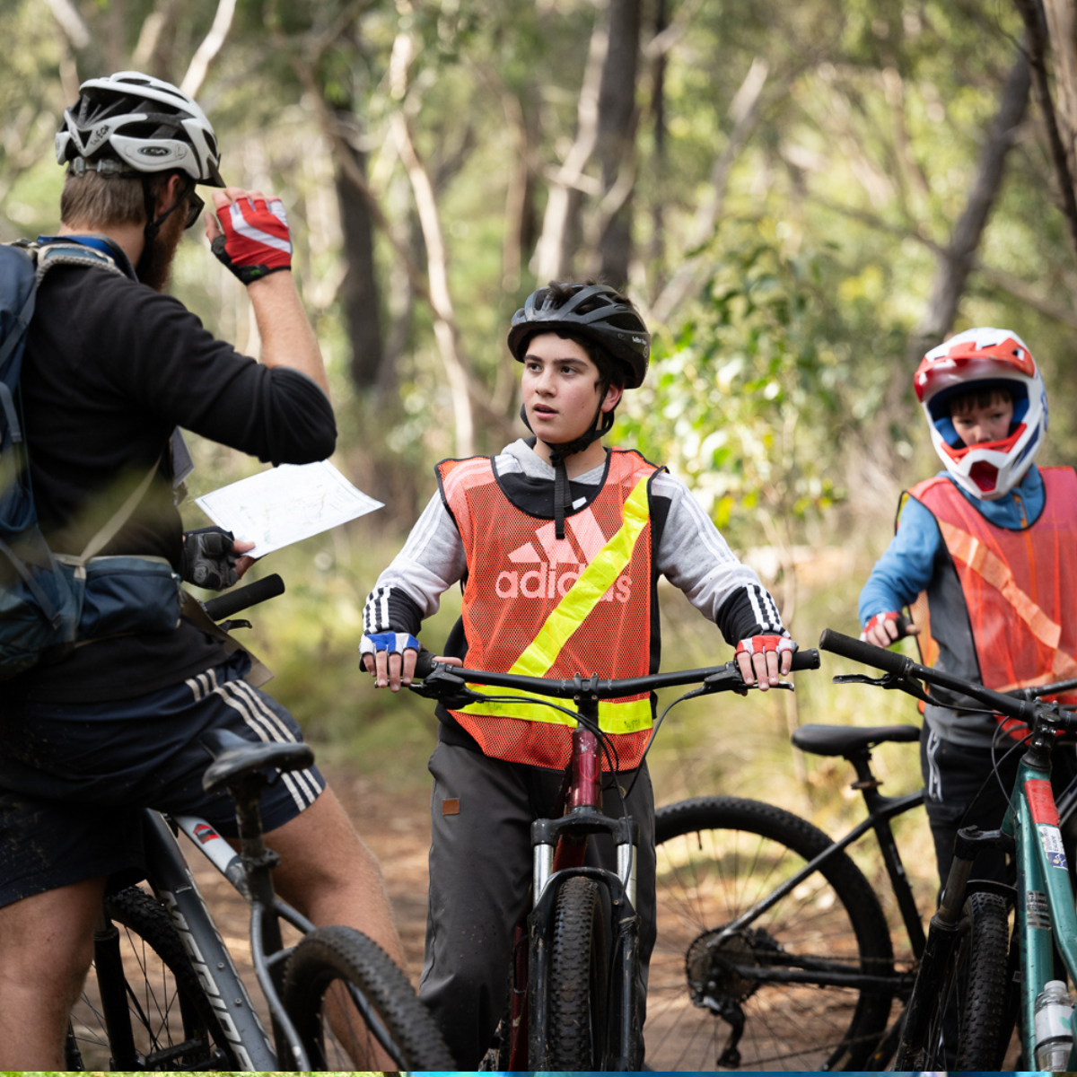 A group of cyclists riding bikes through a lush green forest trail.