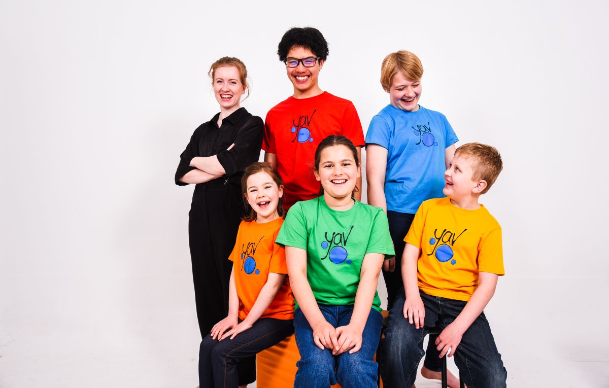 A group of children in bright shirts smiling and posing together for a cheerful photo.