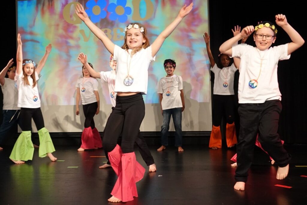 A group of young performers energetically showcasing their talents on stage in front of an audience.