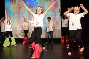A group of young performers energetically showcasing their talents on stage in front of an audience.