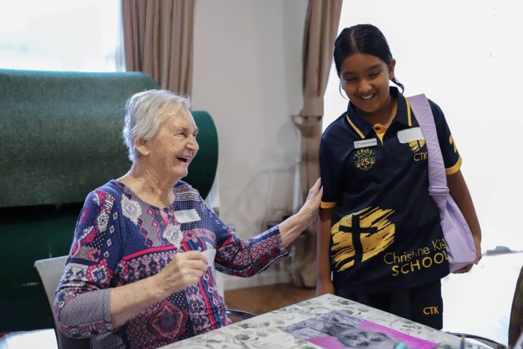A young woman in a school uniform converses with an older woman, both engaged in a thoughtful discussion.