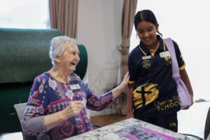 A young woman in a school uniform converses with an older woman, both engaged in a thoughtful discussion.