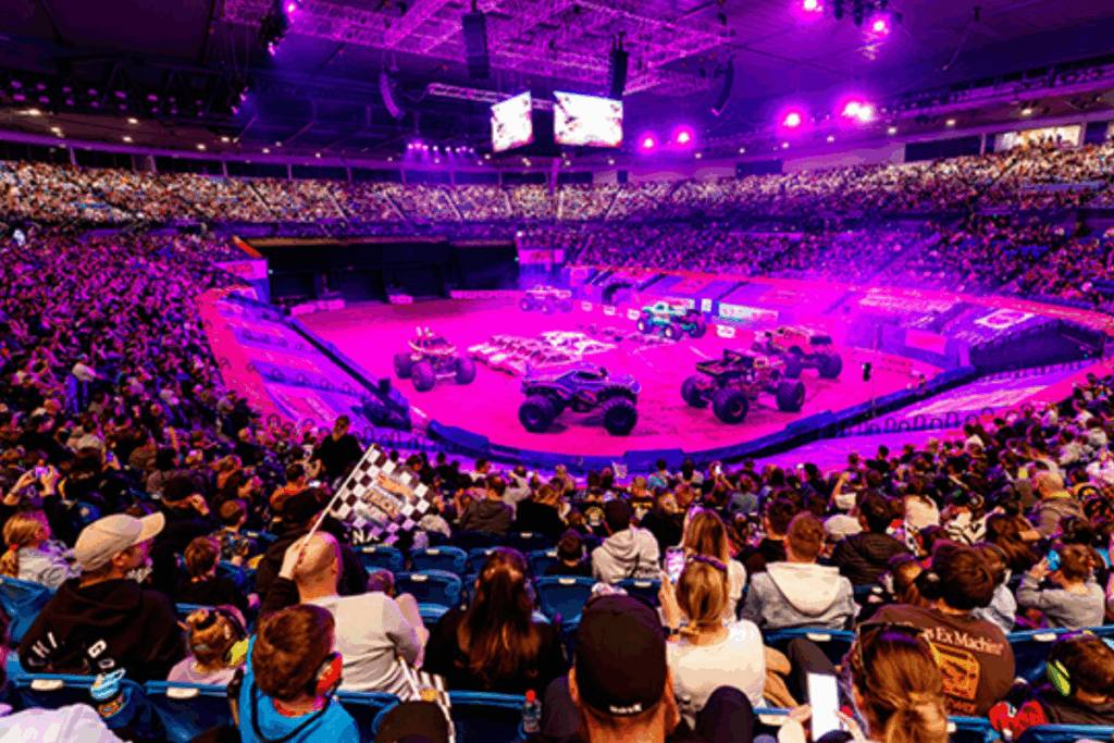 A large crowd of people attentively watching a vibrant circus show under a colorful big top tent.