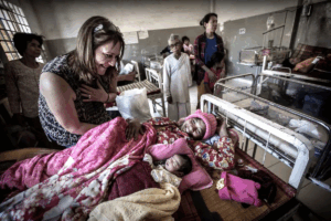 A woman cradles a newborn baby in her arms while resting in a hospital bed.