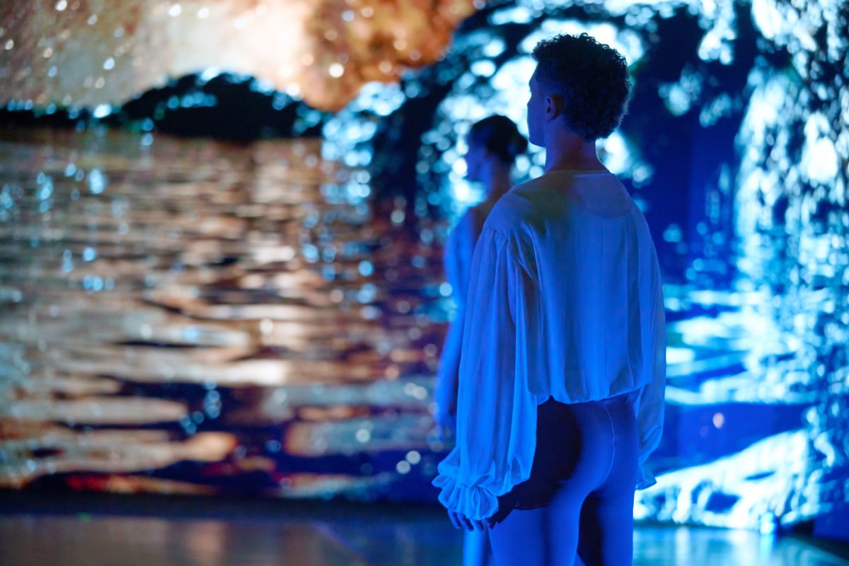  A man stands before a large projection depicting flowing water, creating a serene and immersive atmosphere.