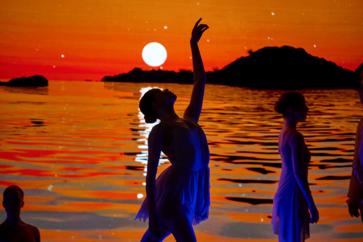 A group of dancers silhouetted against a vibrant sunset, showcasing movement and grace in a colorful sky.