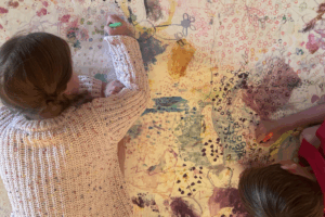 Two children joyfully painting colorful designs on a large mural.