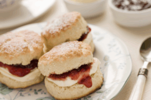 A plate with three freshly baked scones served with a side of jam.