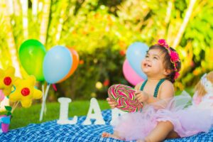 Birthday girl sits on the grass with balloons.