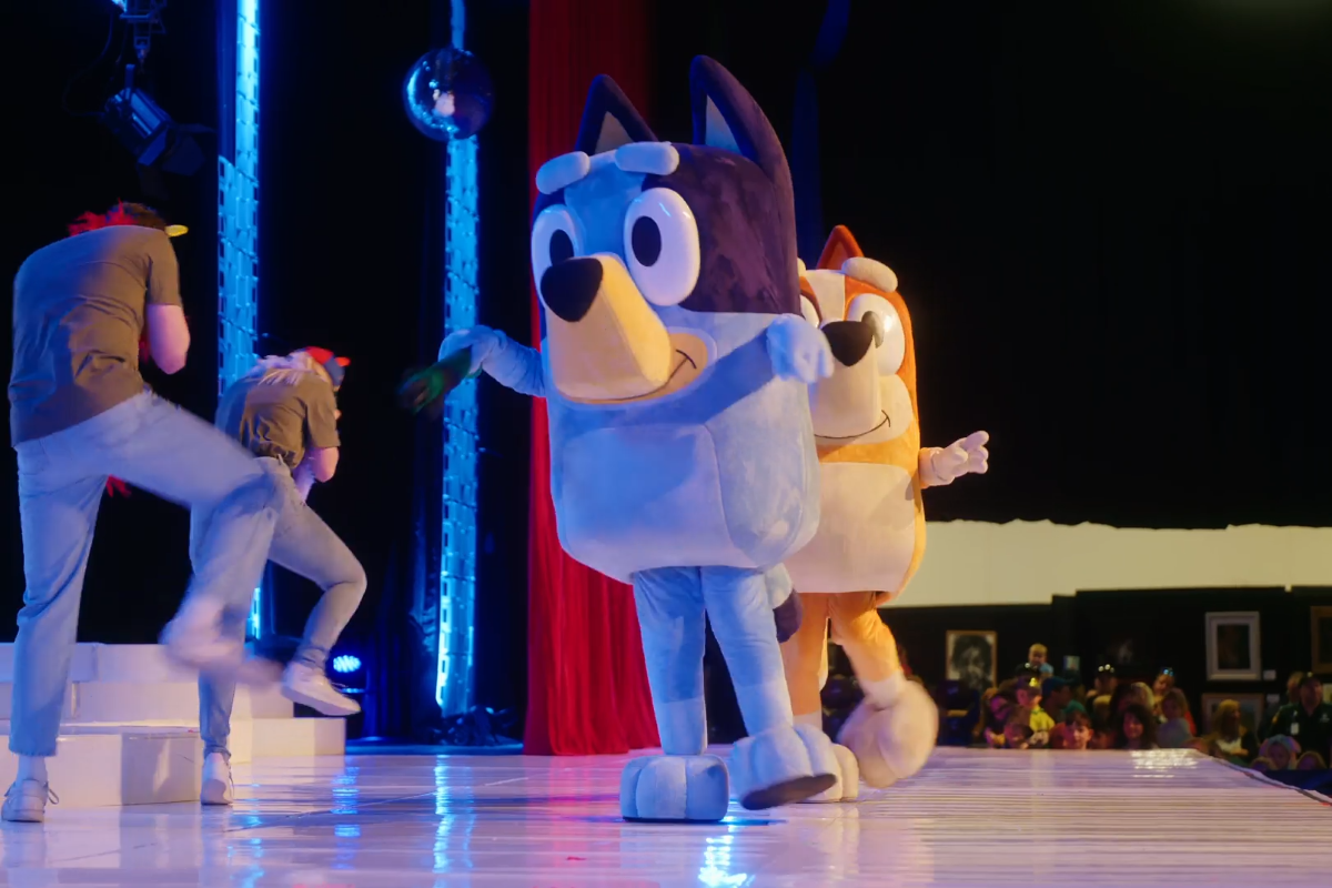Bluey joyfully dances on stage, engaging the audience with lively movements and vibrant energy.