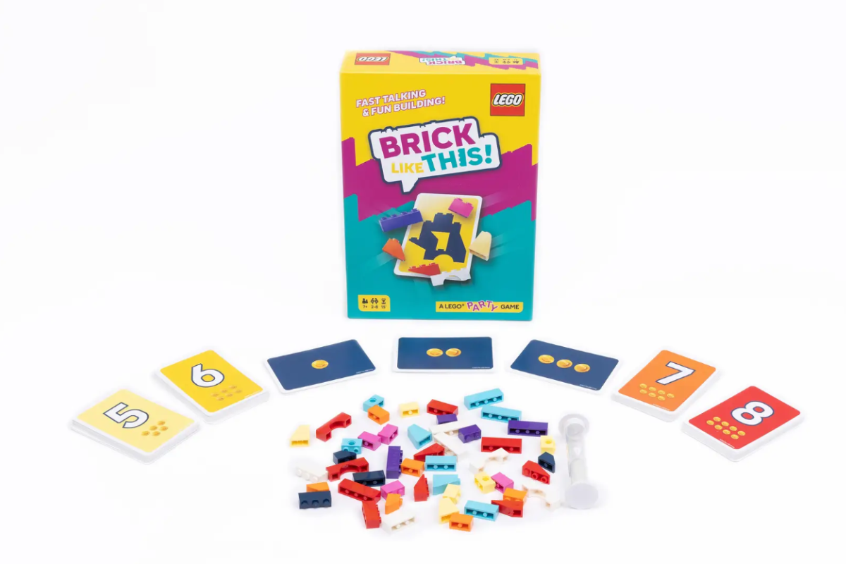  A box of colorful Lego bricks alongside a game board and various game pieces arranged for play.