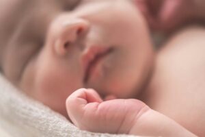 A close-up of a peaceful newborn baby sleeping, with soft features and delicate skin, wrapped in a cozy blanket.