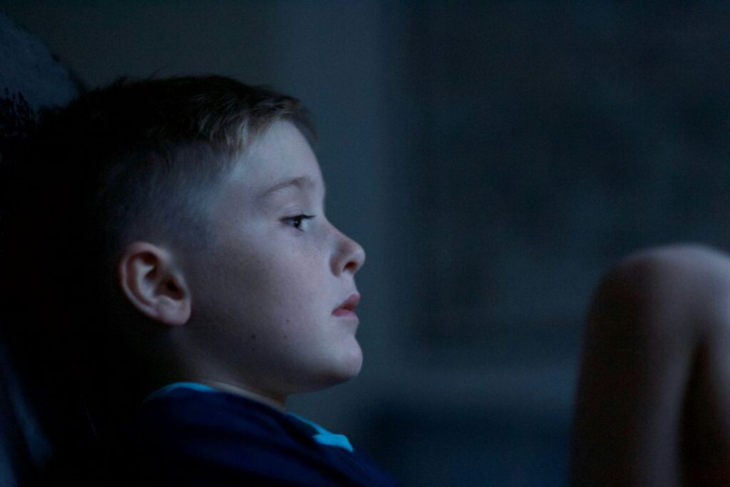 A child sits in the dark, looking stressed.