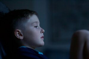 A child sits in the dark, looking stressed.