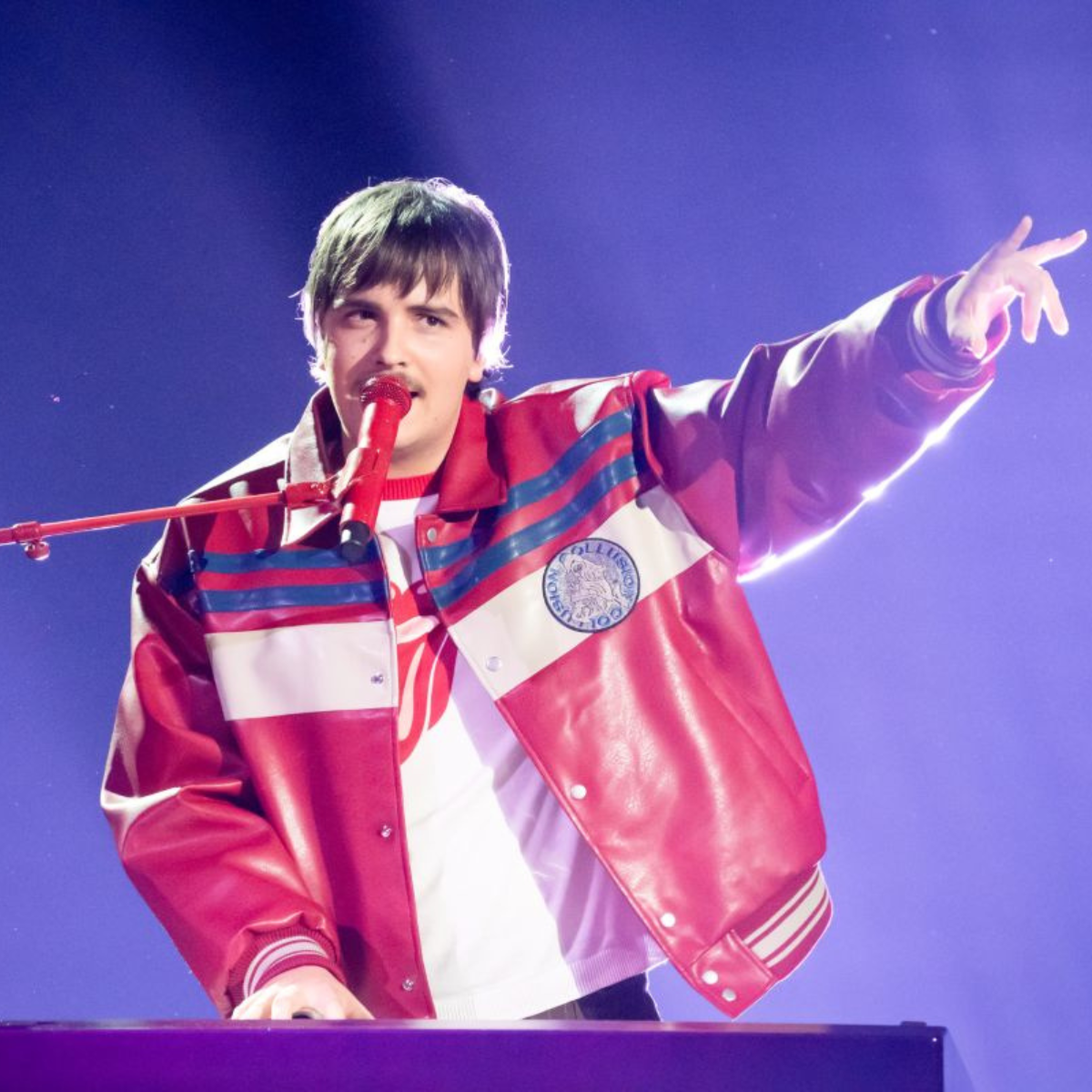 A man in a red jacket holds a microphone
