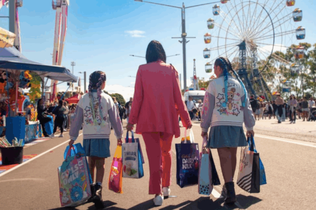 Three girls stroll down a street, each carrying shopping bags, enjoying their day out together.