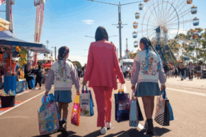 Three girls stroll down a street, each carrying shopping bags, enjoying their day out together.
