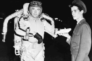 A man in a spacesuit stands holding a piece of paper, set against a backdrop of stars and space.