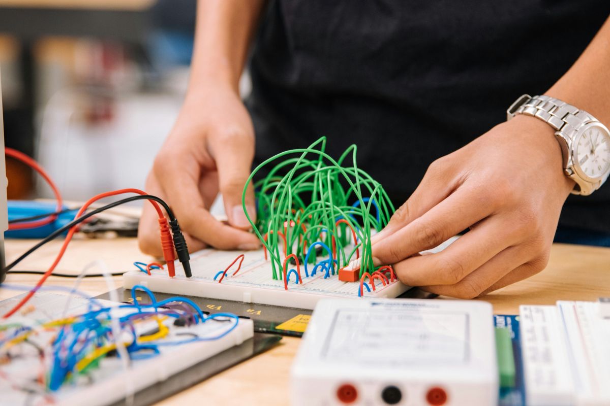 A person focused on electronics, using a laptop while surrounded by various electronic components and tools.
