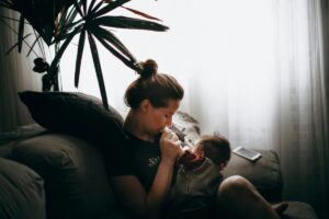 A woman sits on a couch, breastfeeding her baby in a nurturing and comfortable setting.