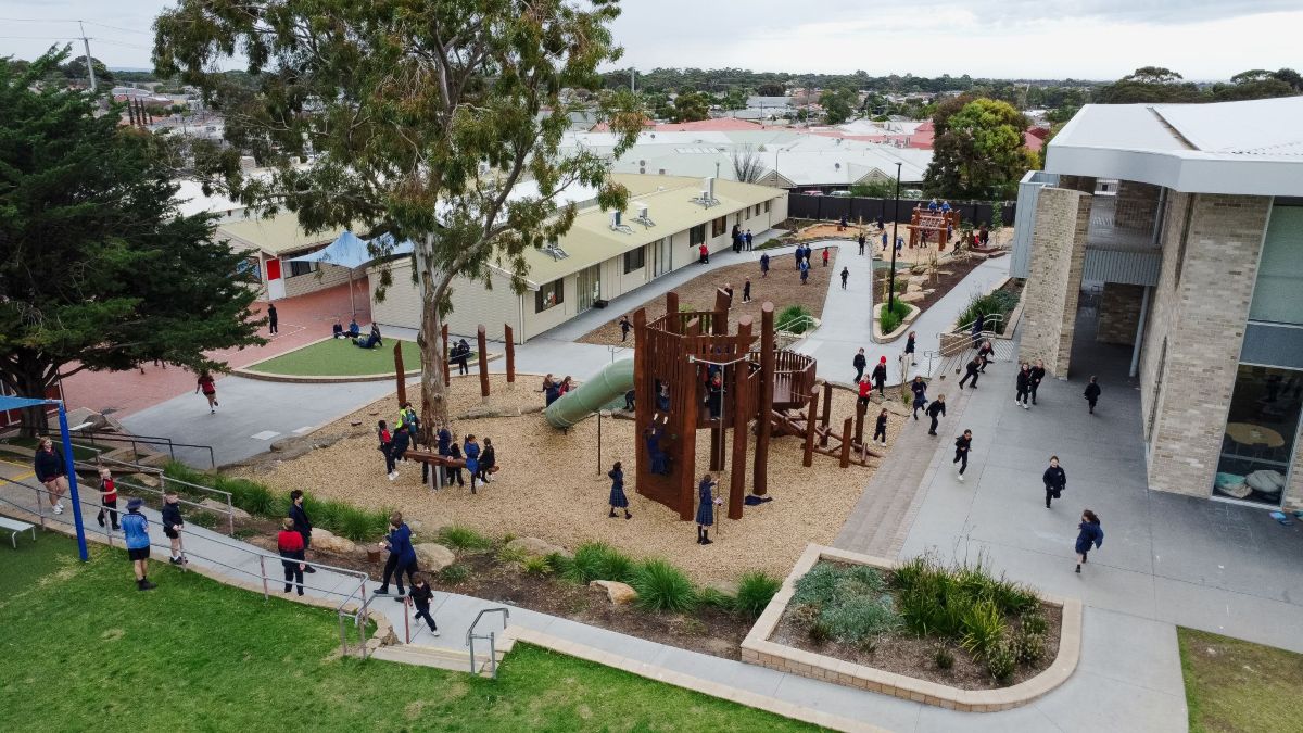 Aerial view of a vibrant playground filled with children joyfully playing on swings, slides, and climbing structures.
