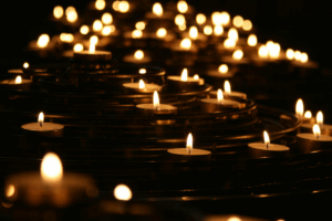 Many candles flicker in a dimly lit room, casting soft shadows and a serene glow.