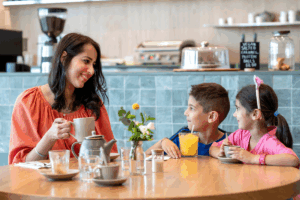 A woman and two children enjoy coffee together at a table, sharing a warm and engaging moment.