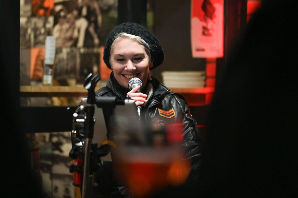  A smiling woman holds a microphone, exuding confidence and enthusiasm.