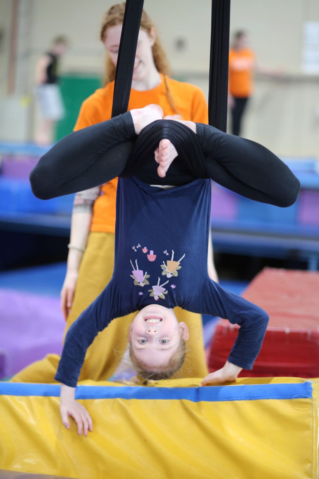 A young girl performs a gymnastics trick on a trampoline, showcasing her agility and balance in mid-air.