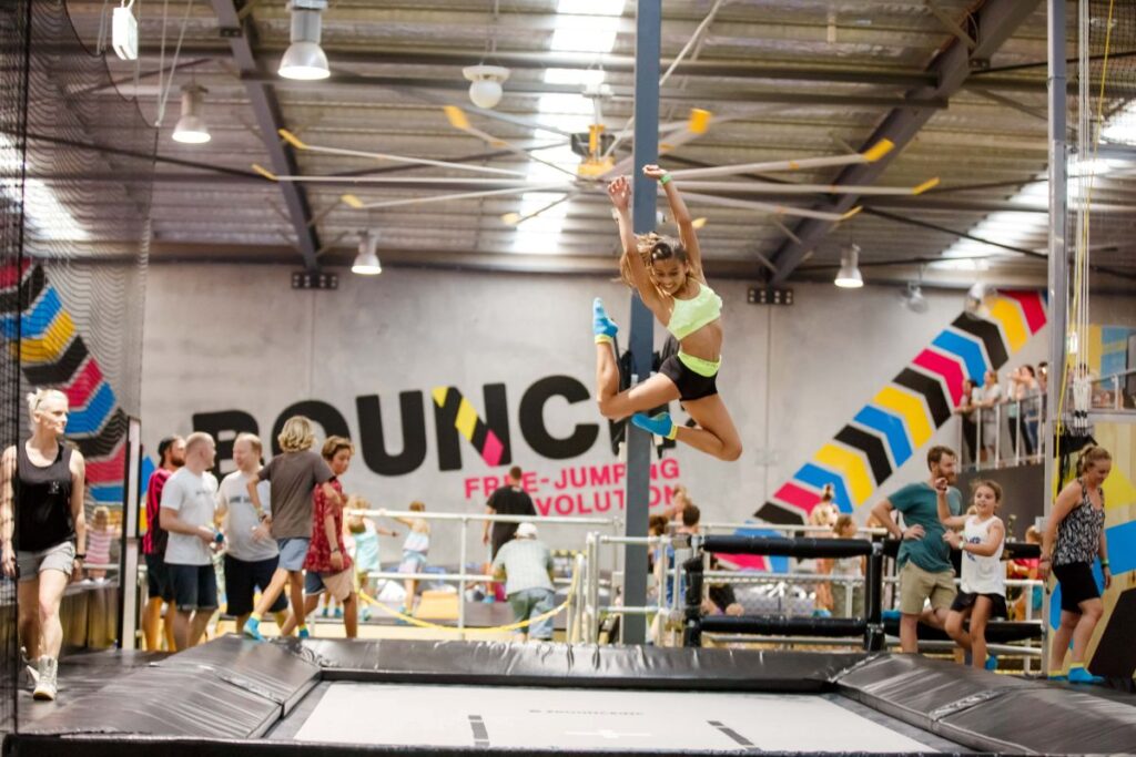 A woman performing a trick on a trampoline inside a gym, showcasing her athleticism and skill.
