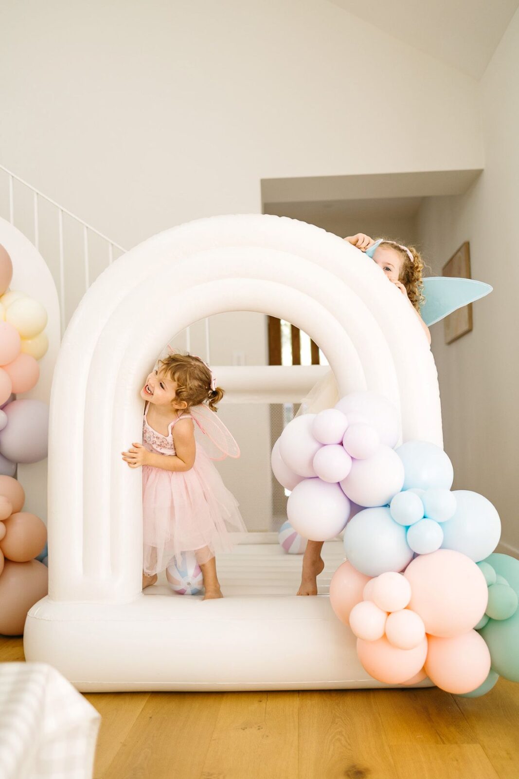 Two young girls joyfully playing together inside a colorful inflatable castle.