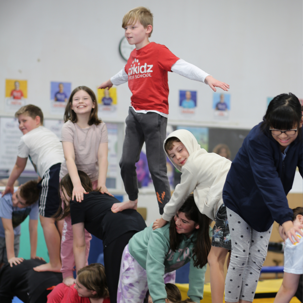 A group of children practicing gymnastics, performing various poses and routines on mats in a bright gymnasium.