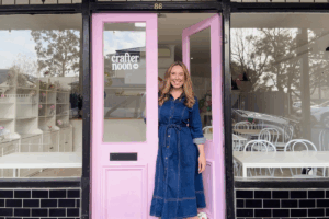 A woman stands confidently in front of a vibrant pink door, showcasing a stylish and inviting entrance.