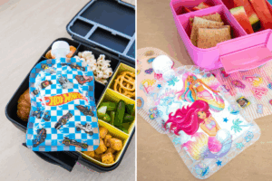 Two colorful lunch boxes filled with snacks and Barbie and Hot Wheels food pouches sitting beside it.