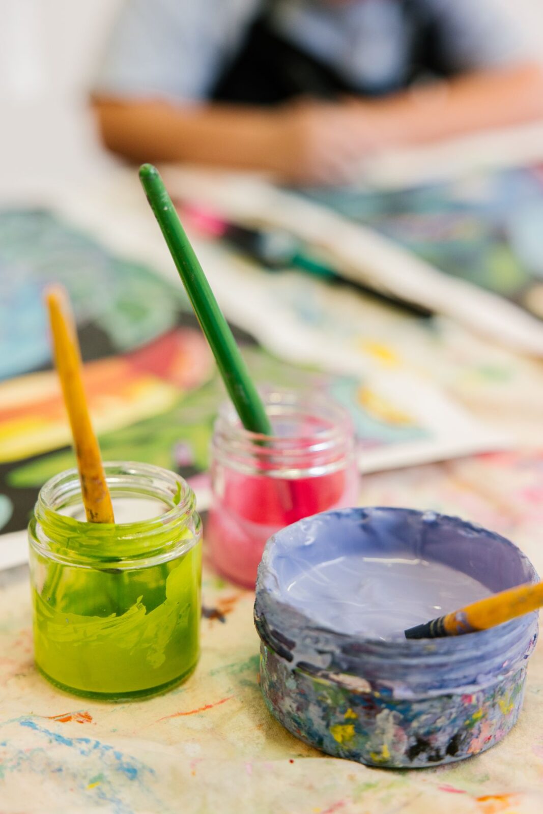 A table displaying various paint colors and brushes arranged for an art project.