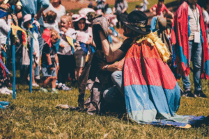 A man in a vibrant cape kneels beside a child, engaging in a playful moment together.