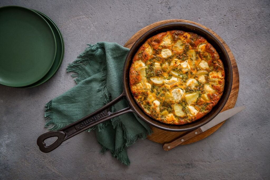 A skillet containing a golden-brown baked dish, garnished and ready to serve.