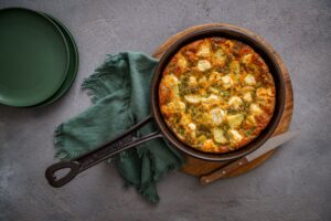 A skillet containing a golden-brown baked dish, garnished and ready to serve.