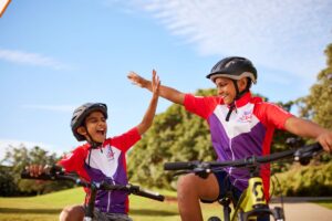 Two boys on bikes share a high five, celebrating their friendship and playful spirit in a sunny outdoor setting.