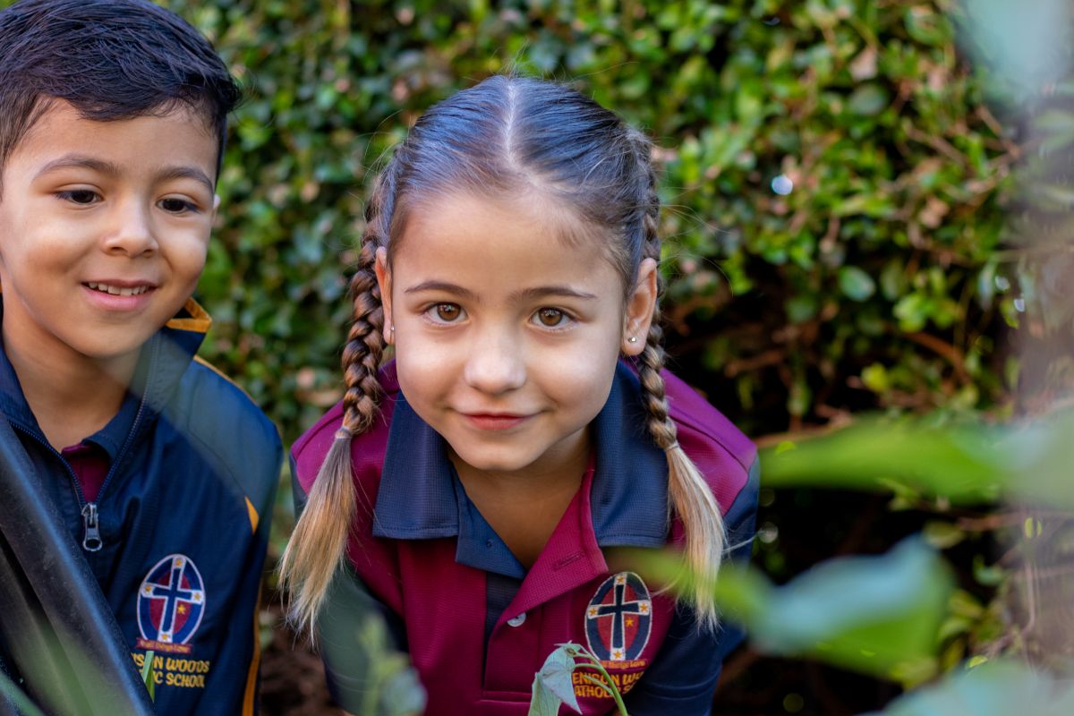 Two young children in school uniforms are smiling happily at the camera.