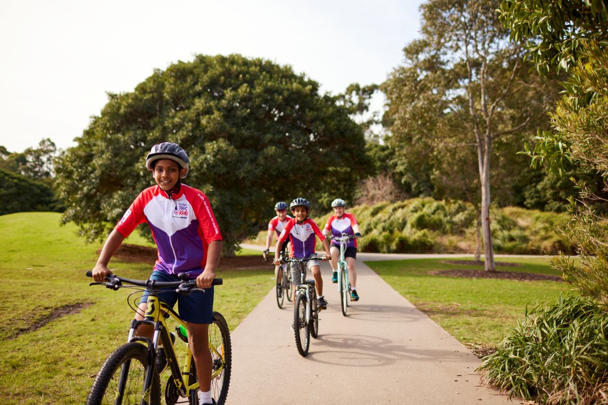  A group of children joyfully riding bikes along a scenic path surrounded by greenery.