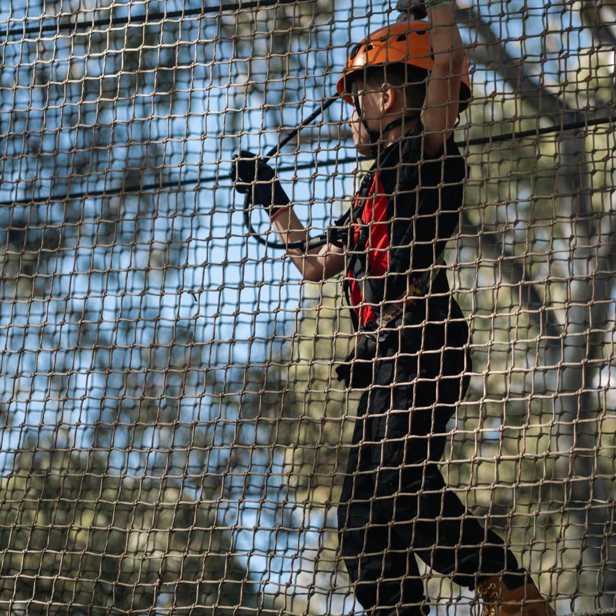 A young boy joyfully rides a zip line