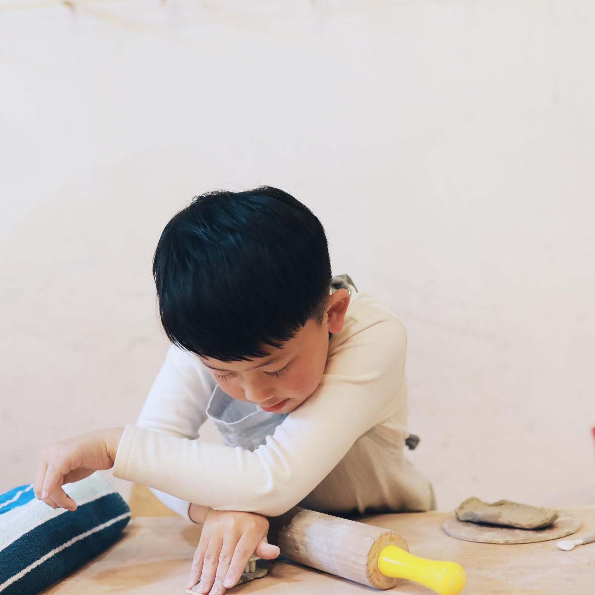 A young boy is focused on creating a craft project with colorful materials spread out on a table.